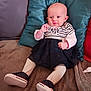 baby, infant, child, couch, pillow, clothing, dress, tights, shoes, striped, sitting, smiling, cute, indoor, soft, comfortable, person, portrait, young, home