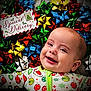 baby, smiling, face, christmas, holiday, festive, onesie, colorful, gift_bows, special_delivery, red, green, yellow, blue, silver, happy, infant, cute, lying_down, celebration