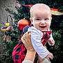 baby, child, smiling, hands, red_checkered_clothing, white_shirt, christmas_tree, ornament, holiday, festive, greenery, lamp, decoration, outdoor, person, portrait, happy, cute, seasonal, celebration