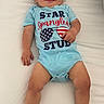 Ronin is registered to the contest to win money with this photo: baby, child, infant, onesie, blue_clothing, smiling, lying_down, hair_spikes, white_background, cute, happy, portrait, person, toddler, skin, legs, feet, hand, american_flag, clothing_text