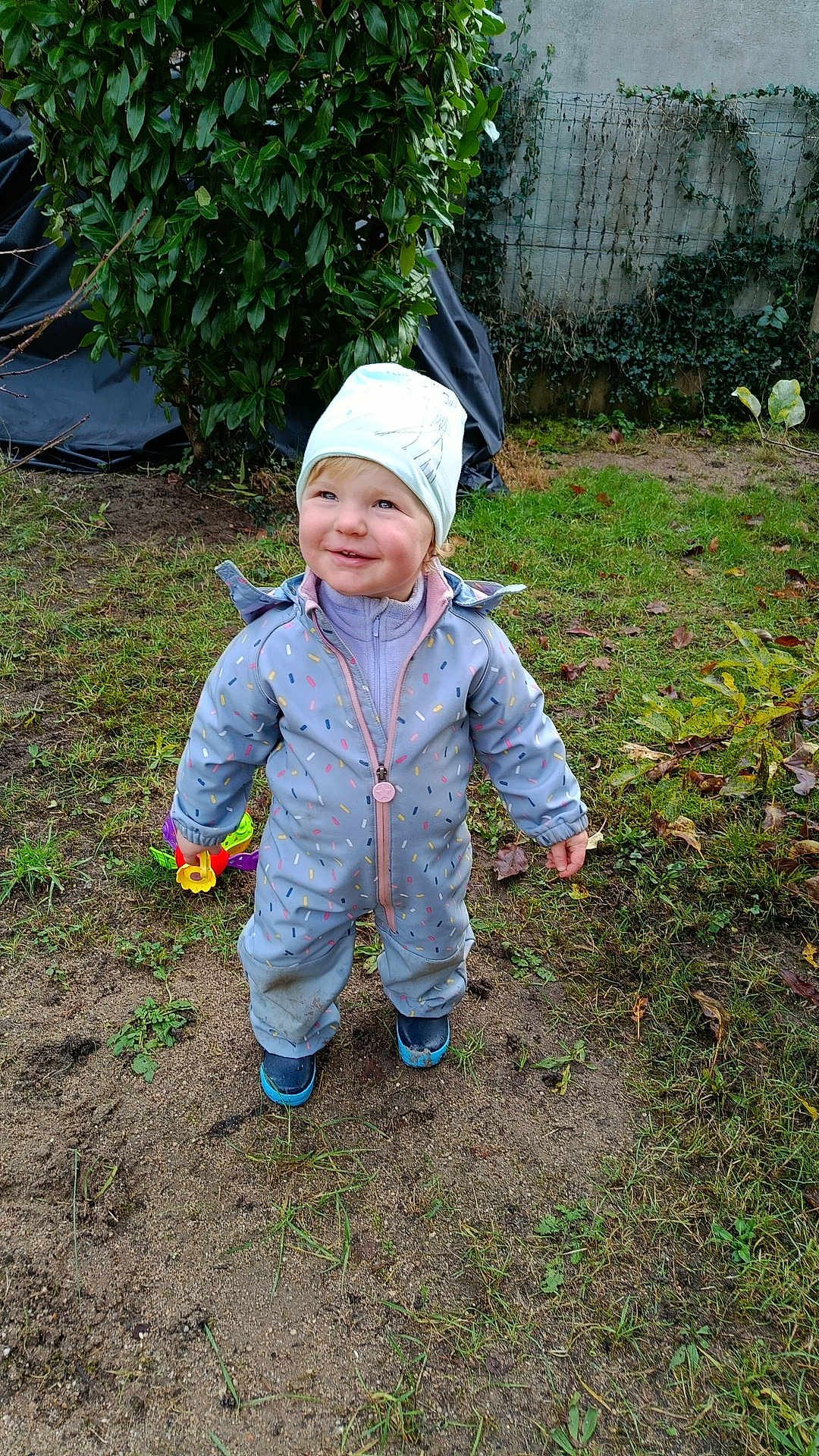 Alissa a rejoint le concours — aidez-le/la à gagner de superbes lots ! toddler, child, outdoor, grass, toy, rain_suit, hat, smile, playful, nature, greenery, garden, fence, happy, person, footwear, fall, leaves, candid, young_child