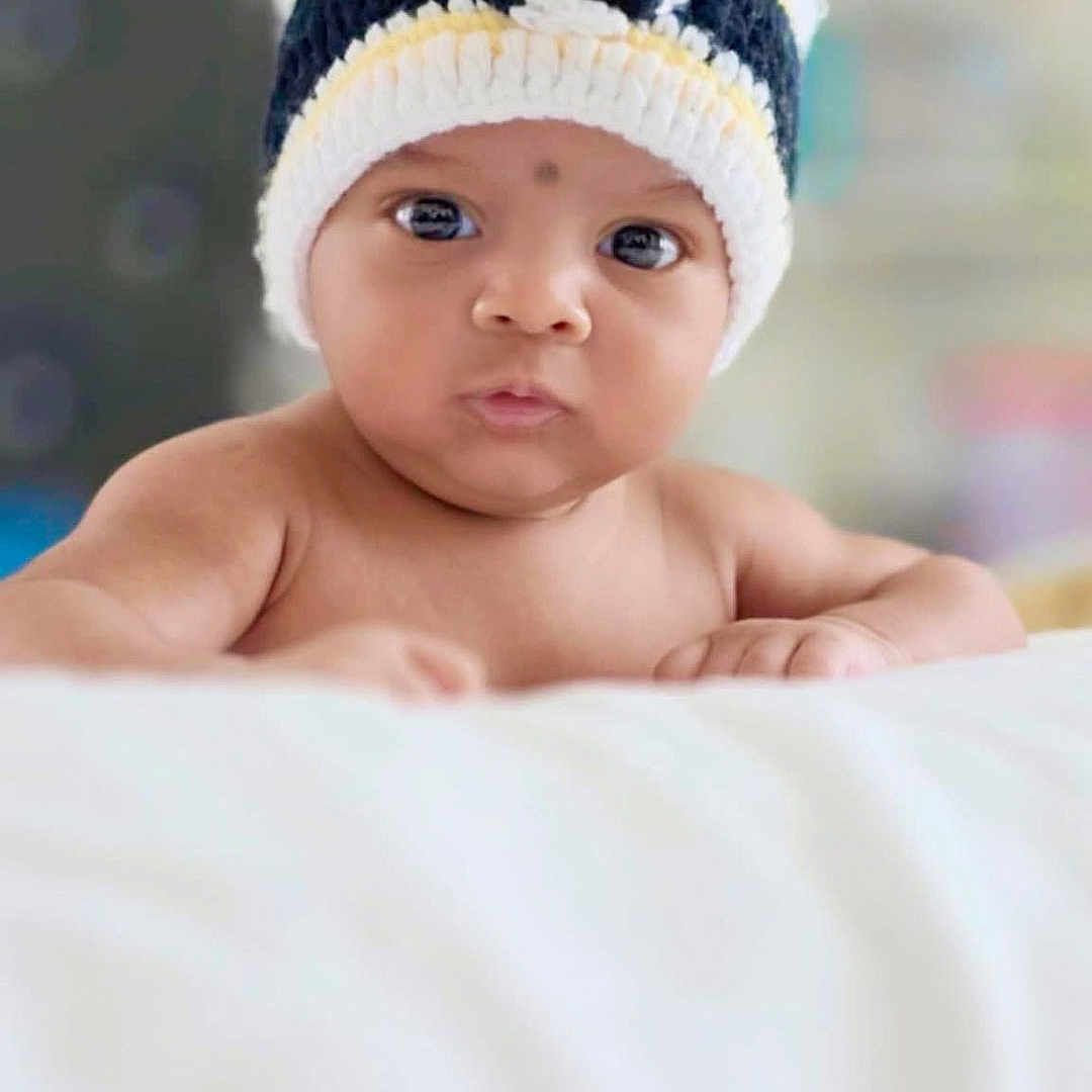 Ayush joined the competition — help win amazing prizes! baby, blanket, child, cute, expression, eyes, face, focus, hat, headwear, indoor, infant, knitted_hat, person, portrait, resting, skin, soft_light, white, young