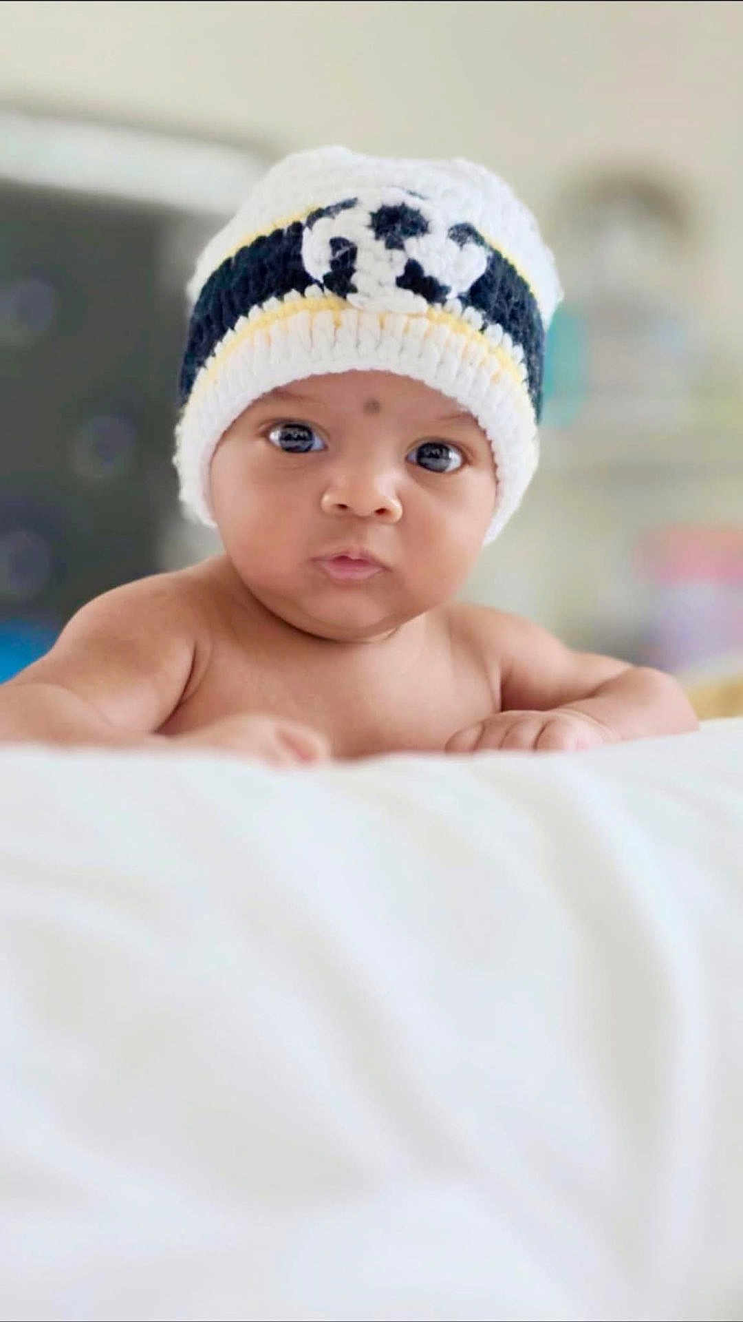 Ayush joined the competition — help win amazing prizes! baby, child, infant, hat, knitted_hat, face, eyes, skin, cute, portrait, indoor, soft_light, focus, expression, young, resting, white, blanket, headwear, person