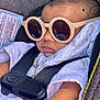 baby, car_seat, sunglasses, child, infant, seatbelt, blanket, clothing, gold_chain, fashion, portrait, cute, accessory, white, black_straps, head, face, skin, relaxing, babywearing