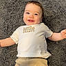 baby, infant, smile, happy, child, lying_down, white_shirt, beige_shorts, carpet, gray_rug, cute, portrait, indoor, person, young_child, baby_clothes, toddler, happy_face, small_child, relaxed