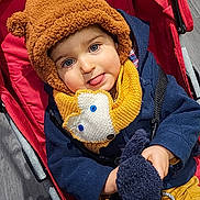 Antonin participe au concours pour gagner de l'argent avec cette photo : baby, bear_hat, blue_eyes, button, child, coat, fabric, hand, hat, plush, portrait, red, scarf, seat, smile, stroller, tongue_out, toy, wood_floor, yellow_pants