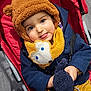 baby, bear_hat, blue_eyes, button, child, coat, fabric, hand, hat, plush, portrait, red, scarf, seat, smile, stroller, tongue_out, toy, wood_floor, yellow_pants
