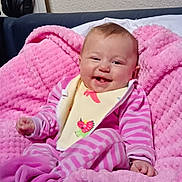 Olivia participe au concours pour gagner de l'argent avec cette photo : baby, pink_blanket, striped_clothing, bib, smiling, infant, sock, cozy, cute, happy, indoor, couch, furniture, face, child, portrait, soft_texture, comfort, relaxed, head