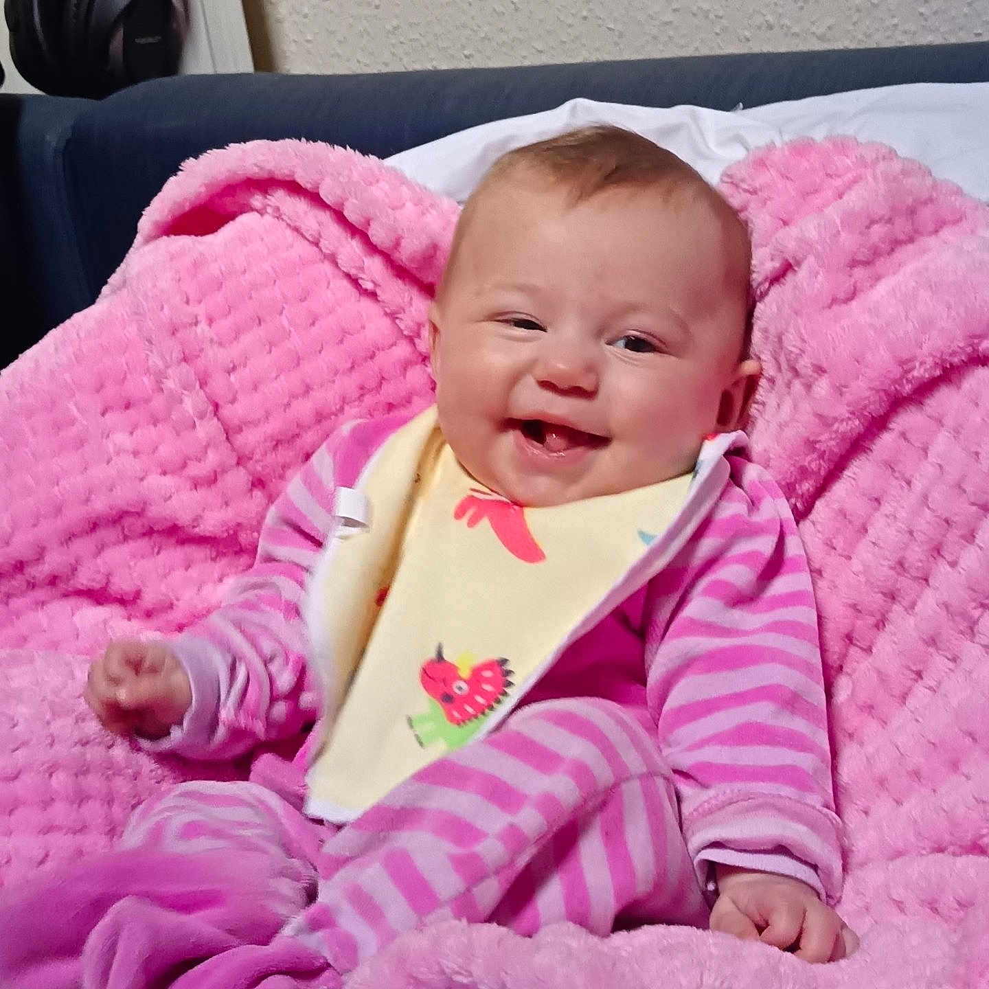 Olivia participe au concours pour gagner de l'argent avec cette photo : baby, pink_blanket, striped_clothing, bib, smiling, infant, sock, cozy, cute, happy, indoor, couch, furniture, face, child, portrait, soft_texture, comfort, relaxed, head