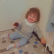Kataleya participe au concours pour gagner de l'argent avec cette photo : toddler, child, smiling, curly_hair, cupcake, indoor, floor, tile_floor, sitting, casual_clothing, socks, wall, corner, happy, portrait, young_child, snack, cozy, cute, affection