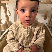 Liam a rejoint le concours — aidez-le/la à gagner de superbes lots ! child, toddler, knitwear, beige, sitting, indoor, toy, brush, wooden, play_gym, curious, face, hands, portrait, cozy, young_child, cute, baby, expression, person