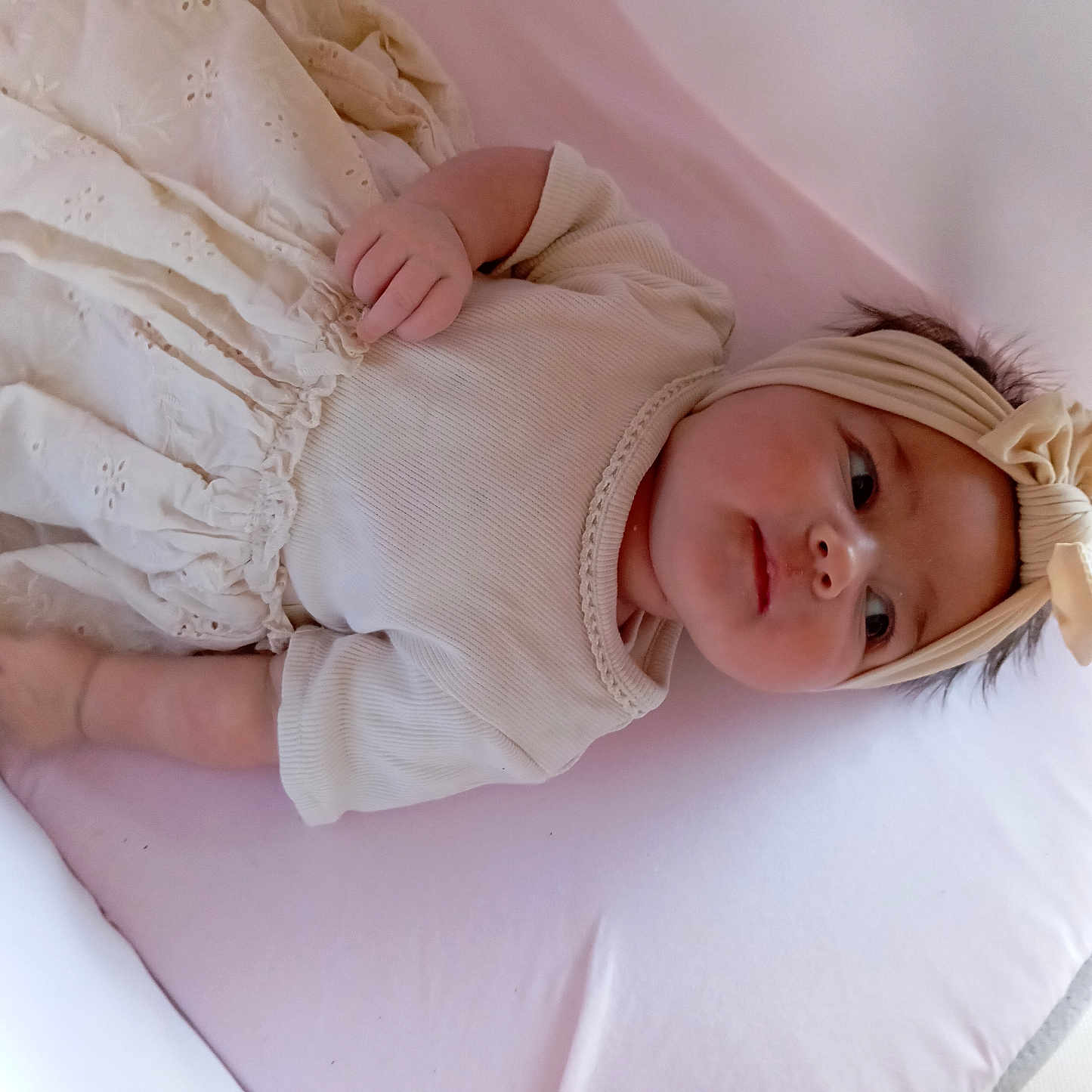 Maewenn a rejoint le concours — aidez-le/la à gagner de superbes lots ! baby, bow, child, clothing, comfortable, cream_color, cute, dress, face, headband, indoors, infant, lying_down, person, pink_cushion, portrait, resting, skin, soft_fabric, young