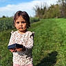 Leynah a rejoint le concours — aidez-le/la à gagner de superbes lots ! child, toddler, outdoor, grass, blue_sky, greenery, person, holding_object, casual_clothing, pink_pants, white_shoes, long_sleeve_shirt, serious_expression, nature, sunlight, shadow, small_person, young_child, playing, daytime