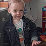 toddler, child, denim_jacket, smile, indoor, toy, playroom, furniture, cute, person, young_child, hair, face, clothing, shirt, hand, expression, home, background, shelf