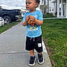Zidane is registered to the contest to win money with this photo: toddler, child, curly_hair, blue_tshirt, black_shorts, sneakers, sidewalk, suburban, grass, houses, parked_cars, outdoor, daytime, holding, walking, person, casual_clothing, cute, young_child, portrait