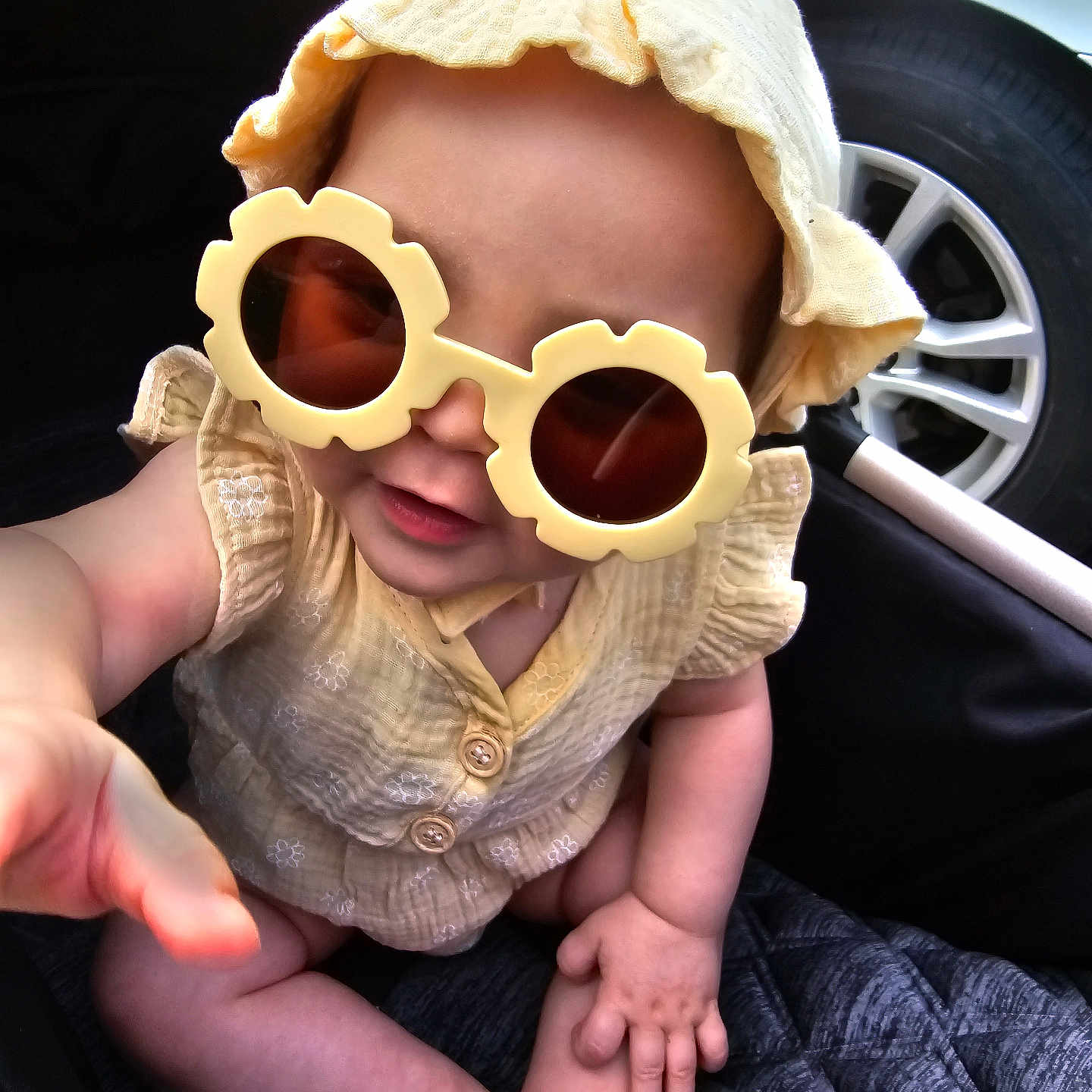 Nala is registered to the contest to win money with this photo: accessories, alloywheel, baby, bodypart, bonnet, cap, car, carwheel, clothing, finger, hand, hat, machine, person, spoke, sunglasses, tire, transportation, vehicle, wheel