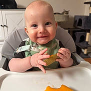 Benjamin joined the competition — help win amazing prizes! baby, child, infant, high_chair, smiling, eating, melon, fruit, food, bib, hands, portrait, indoor, home, kitchen, cat, furniture, tray, happy, close_up