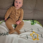Rareș Gabriel participe au concours pour gagner de l'argent avec cette photo : baby, blanket, brown_clothing, child, couch, curious, fabric, face, green, home, indoor, infant, numbers, onesie, portrait, sitting, star_shape, toy, wide_eyes, yellow