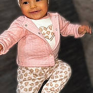 Xymariana is registered to the contest to win money with this photo: baby, bow, child, clothing, cute, face, footed_pants, happy, head, headband, indoors, infant, leopard_print, pajamas, person, pink_jacket, plush, portrait, smiling, soft_toys