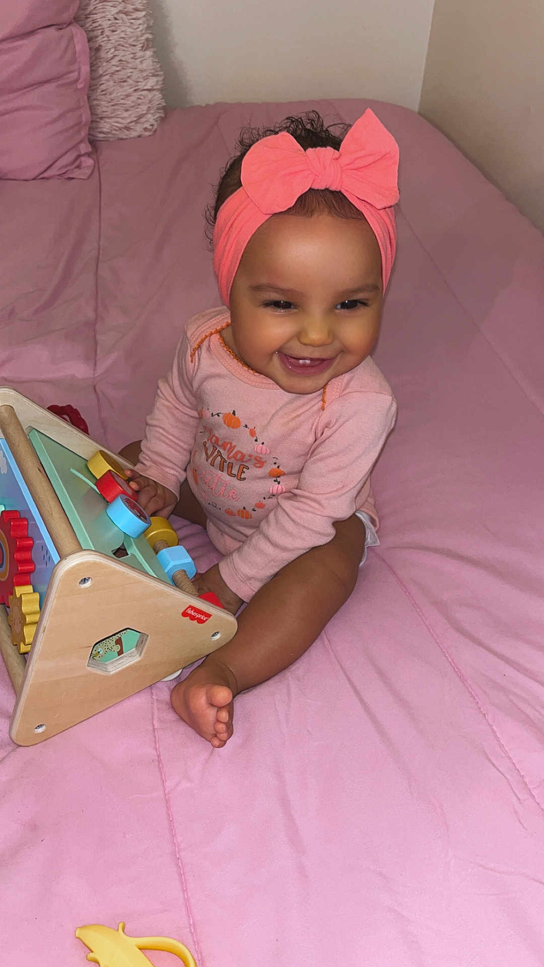 Xymariana is registered to the contest to win money with this photo: baby, bed, blanket, child, clothing, cute, face, foot, girl, happy, headband, indoors, infant, pink, play, room, sitting, smiling, toy, wooden_toy