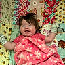 Kinley is registered to the contest to win money with this photo: baby, child, infant, smiling, happy, portrait, lying_down, blanket, pink_blanket, floral_pattern, mittens, striped_clothing, quilt, patchwork, bedding, indoor, play_mat, colorful, face, baby_portrait