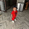 Zamond is registered to the contest to win money with this photo: toddler, child, red_clothing, baseball_cap, smile, indoor, kitchen, floor_tiles, modern_interior, trash_can, refrigerator, wooden_stool, white_sneakers, person, happy, standing, young_child, casual_wear, headwear, cute