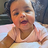 Quinn joined the competition — help win amazing prizes! baby, child, curly_hair, smiling, cushion, pink_clothing, indoors, natural_light, window, happy, face, skin, person, infant, toddler, cute, portrait, soft_texture, home, cozy