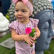 Ainhoa joined the competition — help win amazing prizes! toddler, child, flower, pink_bow, pink_outfit, bracelet, buddha_statue, garden, greenery, grass, cute, portrait, smiling, headband, outdoor, person, nature, statue, happy, baby