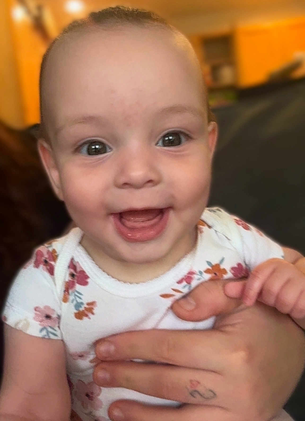 Alora is registered to the contest to win money with this photo: baby, child, smiling, happy, face, hand, floral, clothing, onesie, indoor, person, portrait, cute, infant, human, skin, holding, home, background, expression