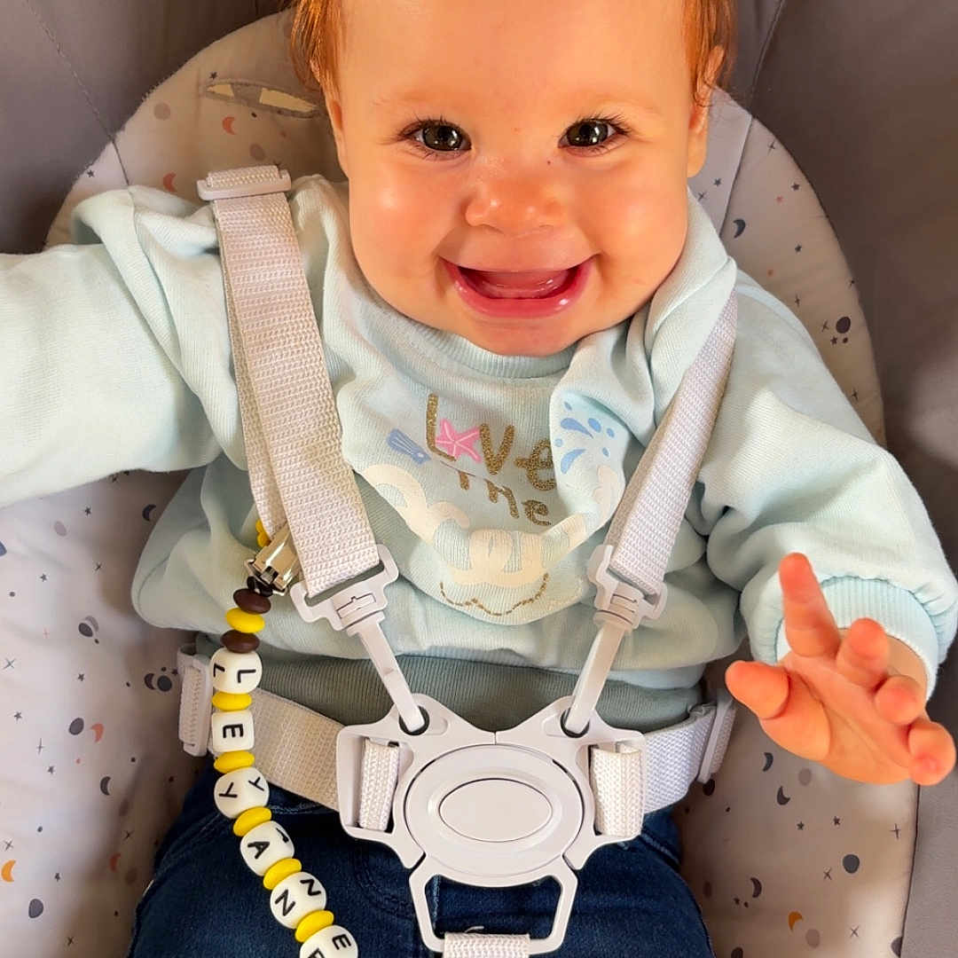 Leyane a rejoint le concours — aidez-le/la à gagner de superbes lots ! baby, baby_seat, child, clothing, comfort, cute, face, hair, happy, indoor, infant, jeans, pacifier, pacifier_clip, person, pony_tail, safety_harness, seated, smiling, sweater