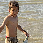 Bilal a rejoint le concours — aidez-le/la à gagner de superbes lots ! boy, child, shirtless, water, river, cloth, holding, standing, outdoor, summer, playful, smiling, shorts, nature, young, person, sunlight, fun, casual, wet