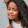 Kasey Gutierrez is registered to the contest to win money with this photo: child, girl, curly_hair, smile, face, hand, wall, texture, portrait, young, happy, playful, skin, jewelry, necklace, bracelet, clothing, dots_pattern, closeup, outdoor