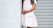 Kasey Gutierrez is registered to the contest to win money with this photo: background, casual, child, concrete, curly_hair, fashion, girl, happy, leaning, outdoor, person, portrait, red_polka_dots, red_sneakers, sidewalk, smiling, standing, urban, wall, white_dress