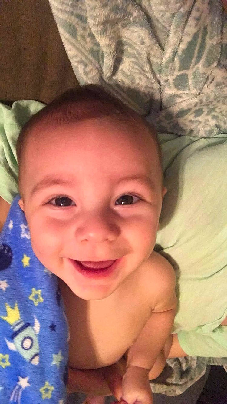 Joziah is registered to the contest to win money with this photo: baby, baby_toddler_clothing, cheek, child, chin, comfort, eyebrow, facial_expression, finger, forehead, happy, human, iris, joy, linens, lip, mouth, nose, person, skin