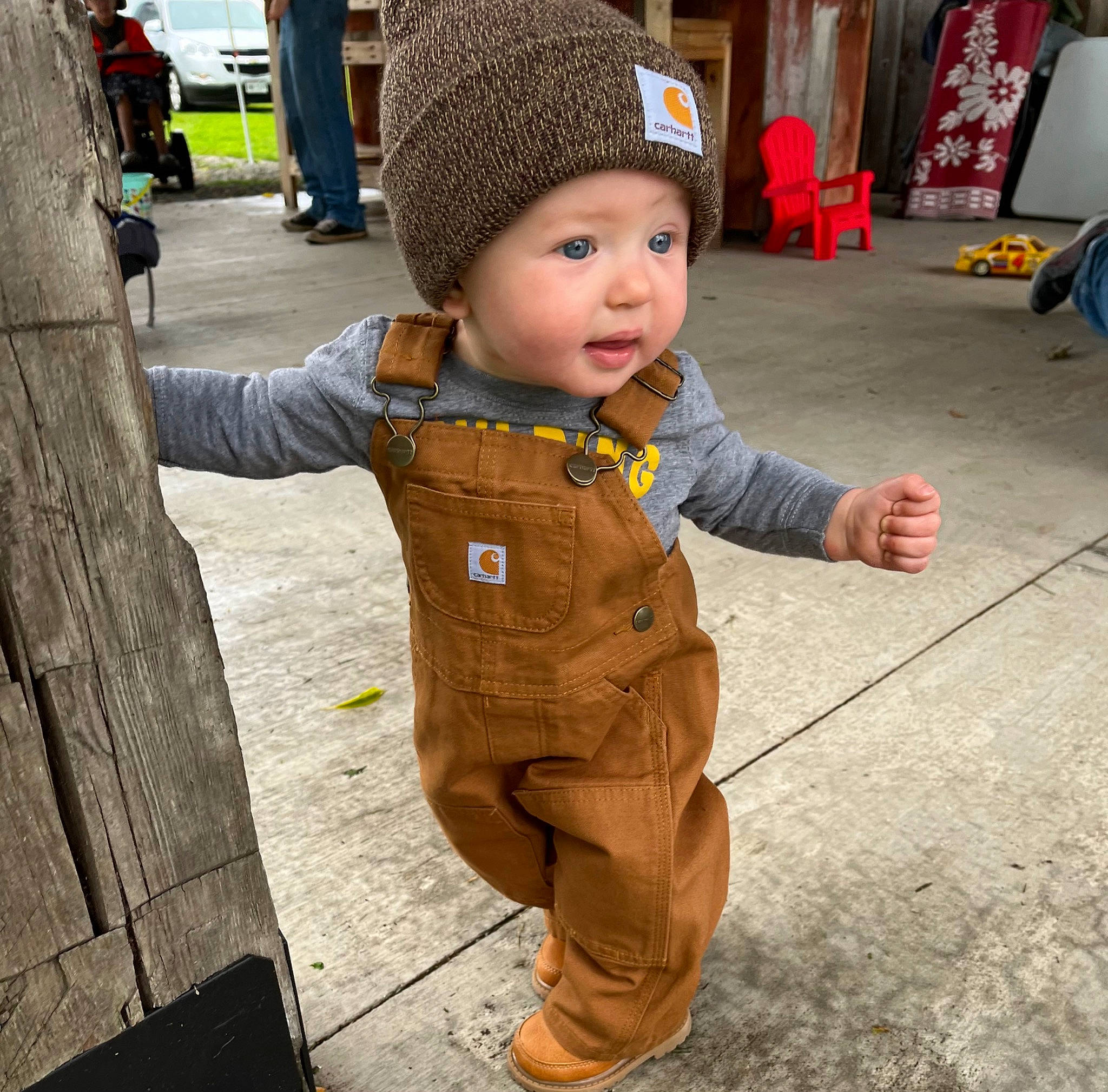 Camden is registered to the contest to win money with this photo: baby, cap, child, eye, face, flooring, fun, head, headwear, jacket, leisure, outerwear, overcoat, person, plant, road_surface, sidewalk, skin, sleeve, smile