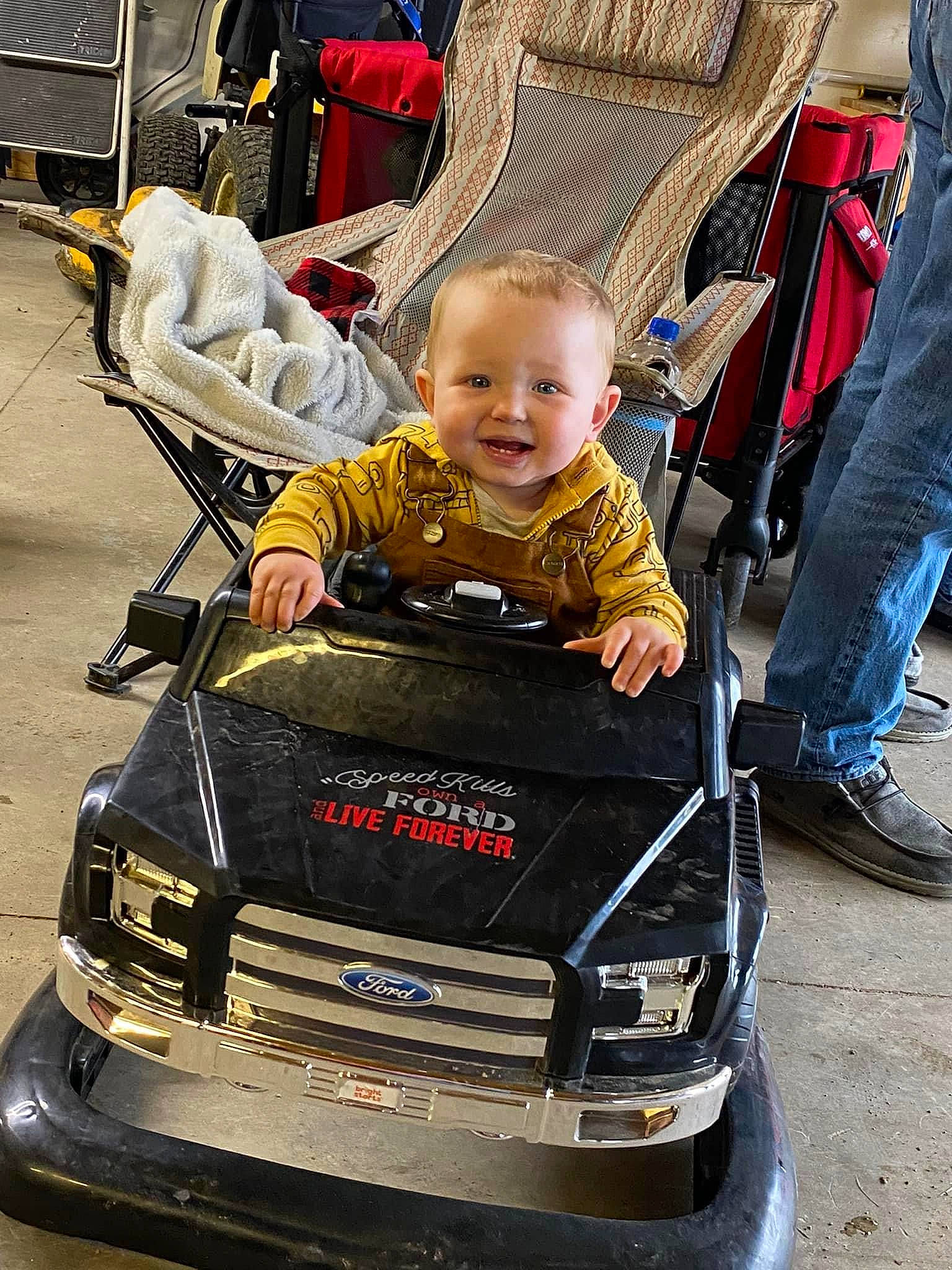 Camden is registered to the contest to win money with this photo: automotive_design, automotive_exterior, automotive_lighting, automotive_tire, bumper, fender, grille, hood, joy, motor_vehicle, person, photograph, shoe, smile, snapshot, sneakers, tire, toddler, vehicle, wheel