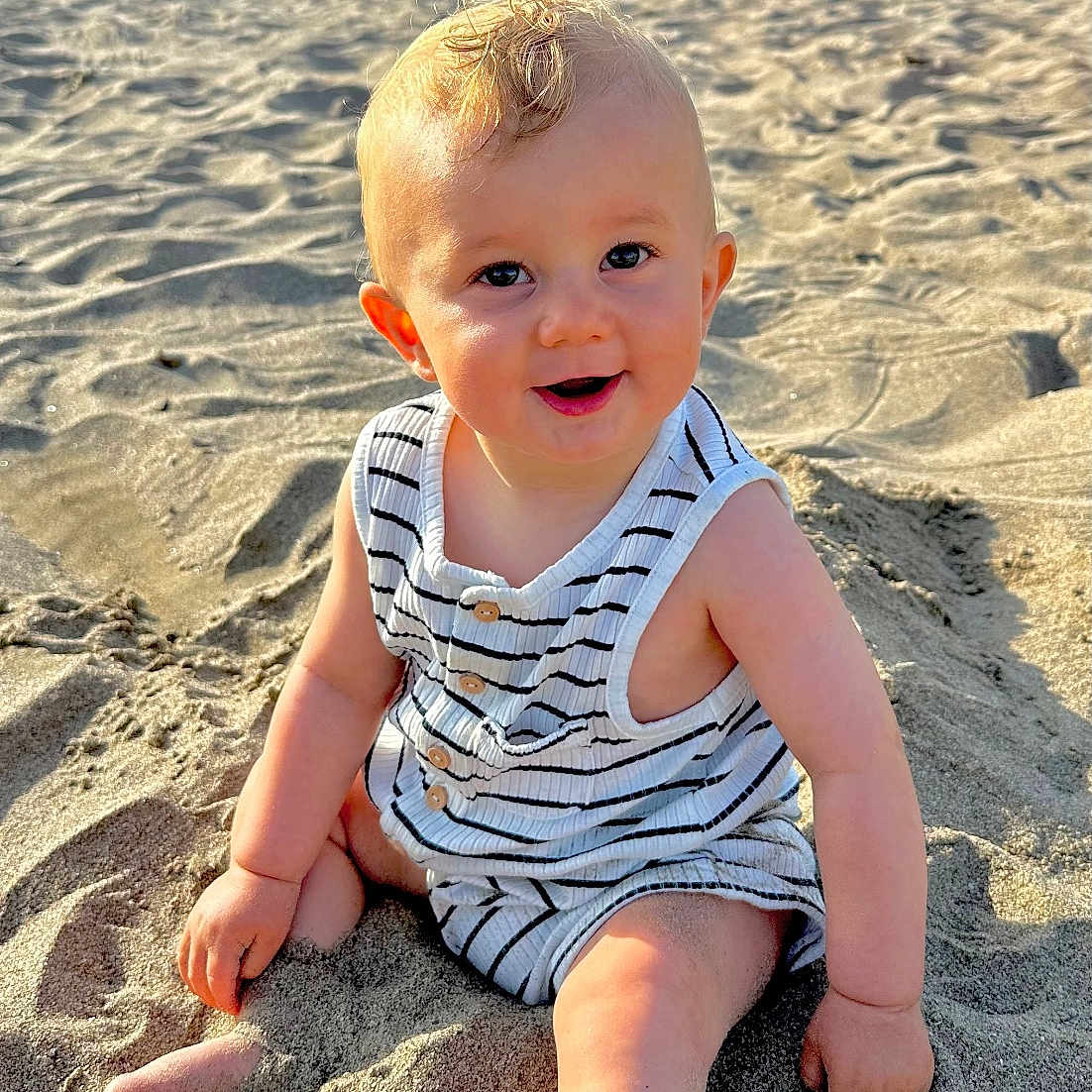 Tiago participe au concours pour gagner de l'argent avec cette photo : baby, beach, blonde, child, clothing, cute, face, foot, hand, happy, nature, outdoor, person, romper, sand, sitting, skin, smiling, summer, sunlight