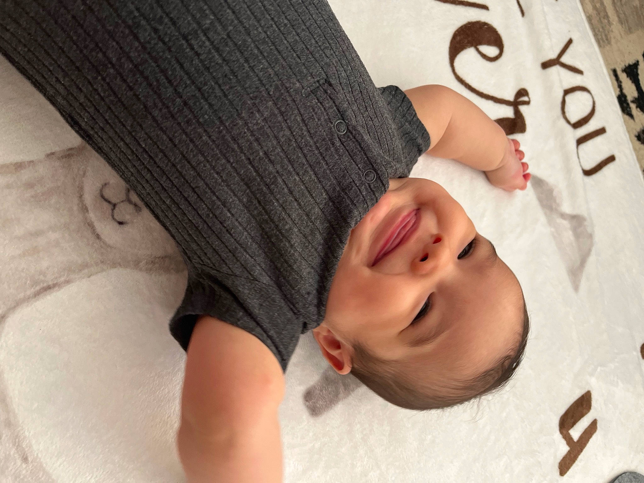 Thayer is registered to the contest to win money with this photo: arm, baby, baby_toddler_clothing, child, chin, comfort, eyelash, finger, hand, happy, headgear, joy, linens, mouth, nail, neck, pattern, person, skin, sleeve