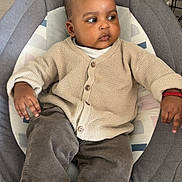 ïssah participe au concours pour gagner de l'argent avec cette photo : baby, baby_seat, casual_clothing, child, child_care, comfortable, cozy, cushion, cute, floor, hand, indoor, infant, looking_away, pants, person, ring, sock, sweater, wood_floor