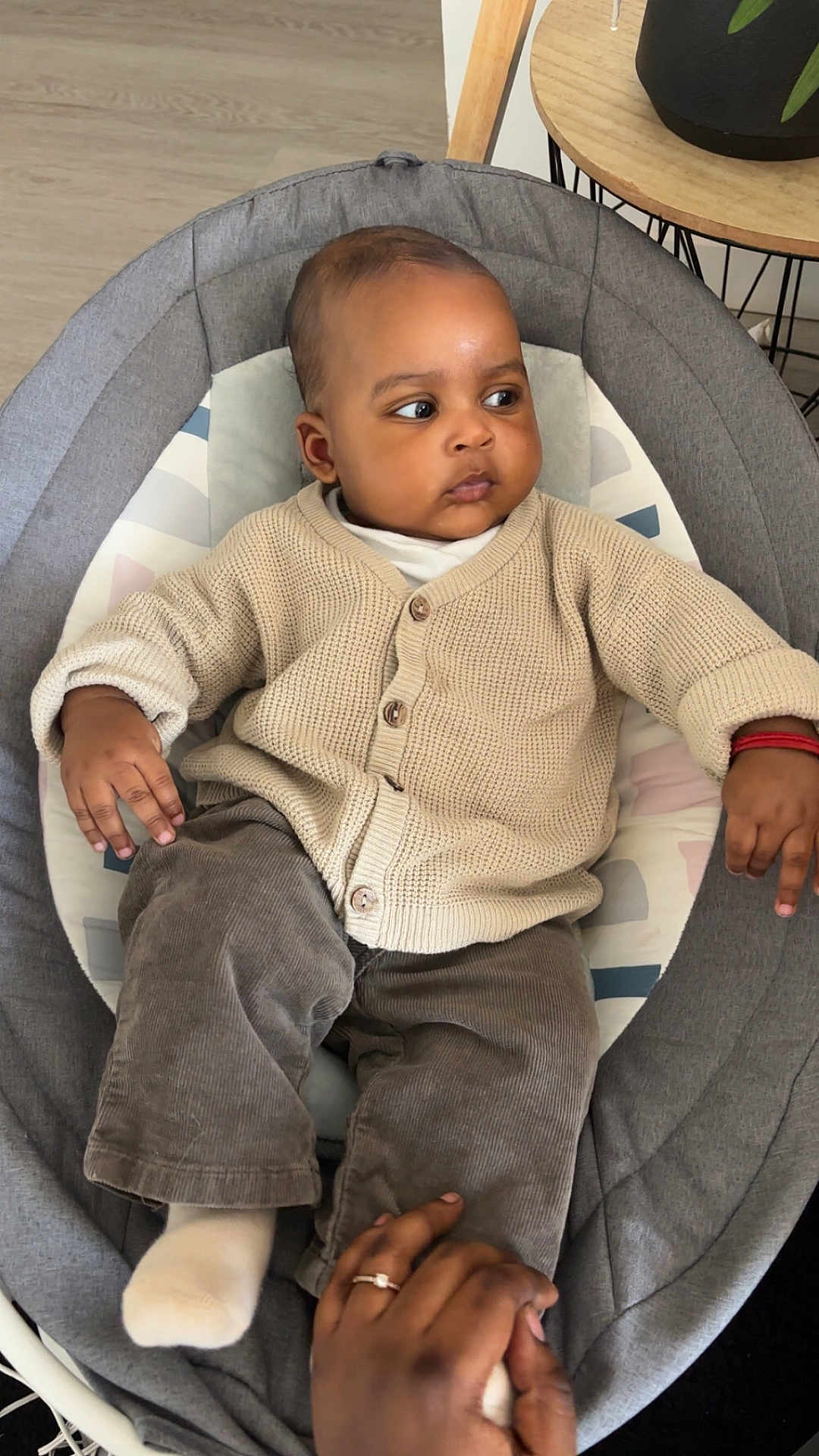 ïssah participe au concours pour gagner de l'argent avec cette photo : baby, baby_seat, casual_clothing, child, child_care, comfortable, cozy, cushion, cute, floor, hand, indoor, infant, looking_away, pants, person, ring, sock, sweater, wood_floor