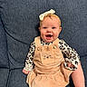 baby, child, infant, smiling, happy, sitting, portrait, face, headband, bow, overalls, leopard_print, cat_design, couch, indoor, blue_background, fashion, cute, legs, photography