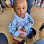 Chosen is registered to the contest to win money with this photo: toddler, child, popcorn, snack, hoodie, sneakers, indoor, person, bucket, floor, hand, clothing, curious, young_child, standing, people, casual, food, playful, expression