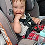 toddler, car_seat, child, baby_bottle, car_interior, smiling, seatbelt, plaid_pants, gray, safety, cute, travel, infant, hand_in_mouth, seat, window, door, headrest, happy, young_child
