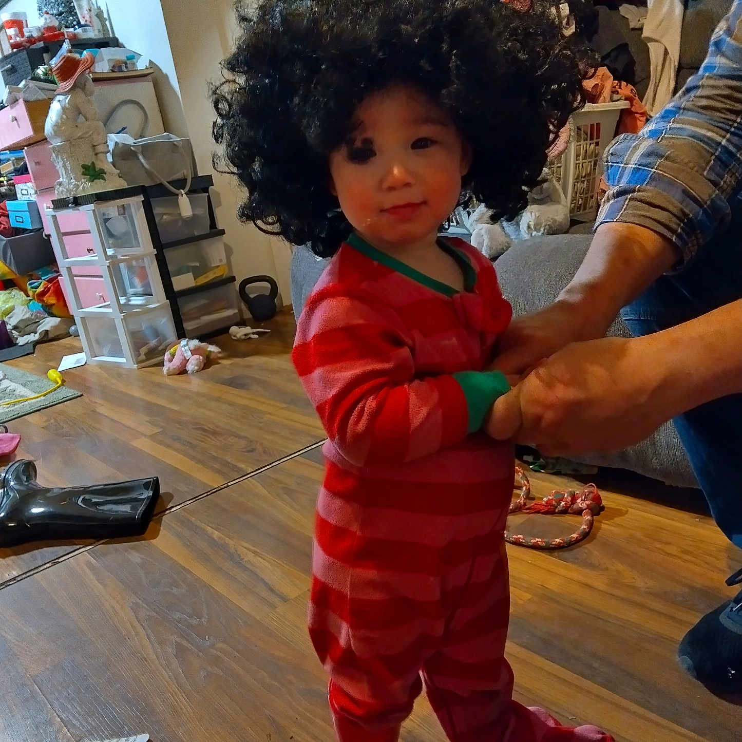 Eva joined the competition — help win amazing prizes! adult_hands, boots, casual, child, clutter, cute, floor, footwear, furniture, hair, indoor, living_room, pajamas, person, plush_toy, storage_drawers, toddler, toy, wig, wooden_floor