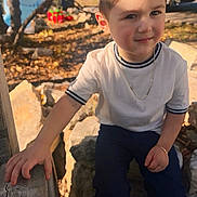 Domingo joined the competition — help win amazing prizes! child, boy, portrait, smile, face, chain_necklace, bracelet, white_shirt, jeans, hand, wooden_rail, rocks, leaves, autumn, sunlight, shadow, sitting, outdoors, close_up, short_hair