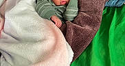 Noraa joined the competition — help win amazing prizes! baby, sleeping, blanket, cushion, green_fabric, brown_cushion, infant, peaceful, cozy, soft_texture, wrapped, child, indoors, resting, cute, person, portrait, young_child, toddler, clothing