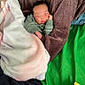 baby, sleeping, blanket, cushion, green_fabric, brown_cushion, infant, peaceful, cozy, soft_texture, wrapped, child, indoors, resting, cute, person, portrait, young_child, toddler, clothing