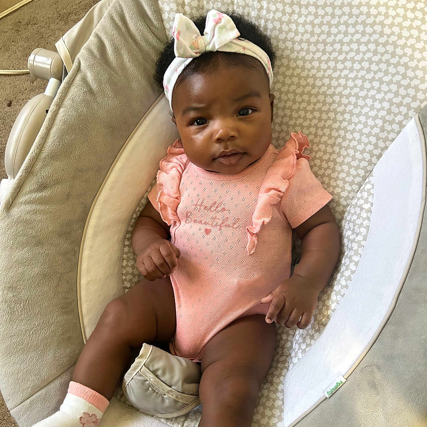 Nazarai Henry is registered to the contest to win money with this photo: baby, baby_seat, bow, carpet, child, comfortable, cute, face, hand, headband, indoors, infant, legs, looking, onesie, patterned_fabric, portrait, skin, socks, young