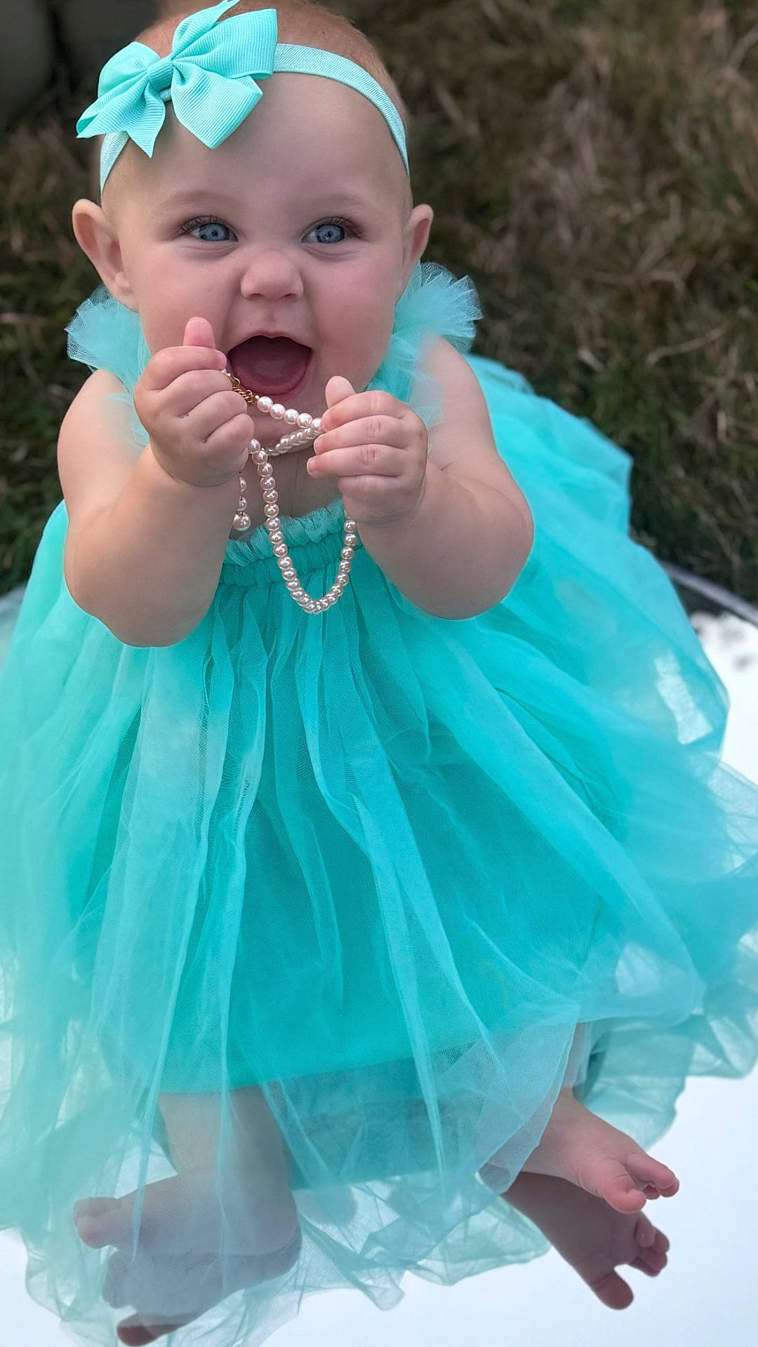 Ceaira joined the competition — help win amazing prizes! baby, barefoot, blue_eyes, celebration, child, cute, dress, fashion, grass, happy, headband, infant, jewelry, necklace, outdoor, pearl, person, portrait, smile, tulle