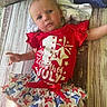 baby, celebration, child, clothing, cute, expression, festive, floor, fourth_of_july, holiday_outfit, indoors, infant, laying_down, patriotic, person, red_shirt, skirt, star_pattern, toddler, wooden_floor